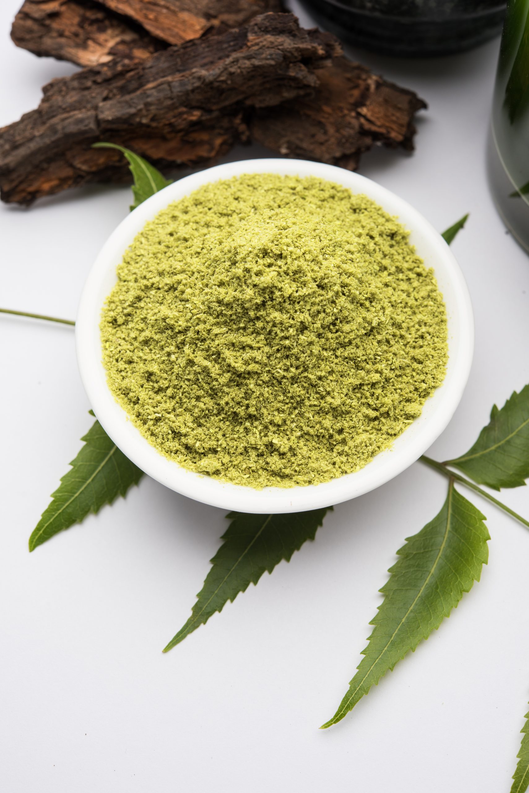 Medicinal Ayurvedic Azadirachta indica or Neem leaves in mortar and pestle with neem paste, juice and twigs, powder and oil, selective focus Medicinal Ayurvedic Azadirachta indica or Neem leaves in mortar and pestle with neem paste, juice and twigs, powder and oil, selective focus
