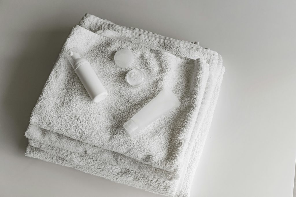 Elegant arrangement of white towels and beauty products in a clean, minimalist setting.