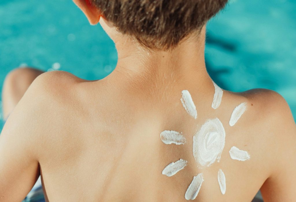 Child's back with sunscreen in sun shape, enjoying a sunny day by the pool.